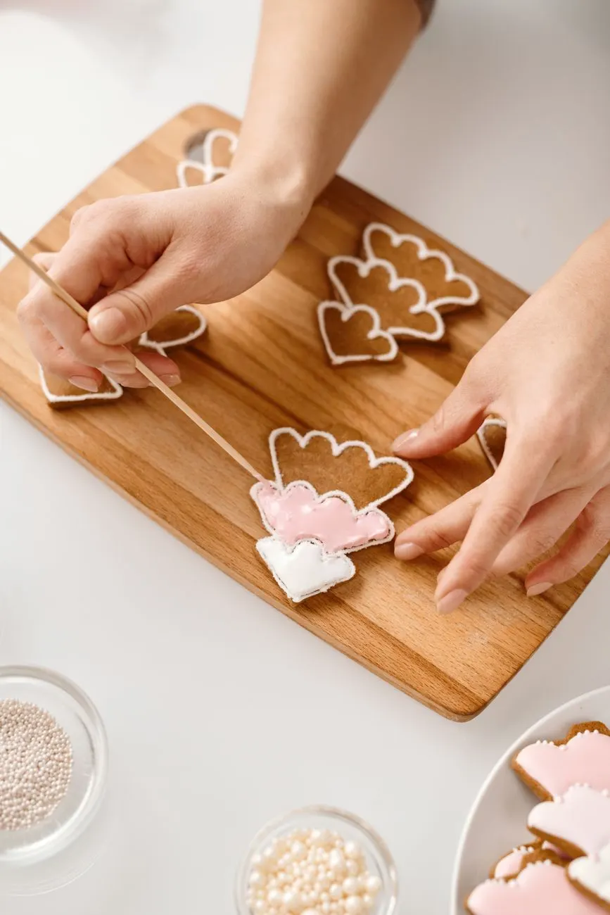 Hands decorating cookies with pink royal icing